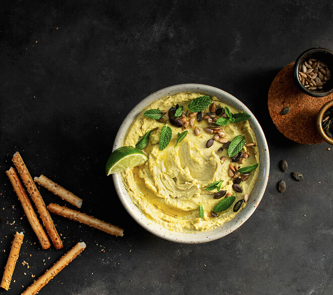 Hummus in a bowl on a black background by Limitech machine. 